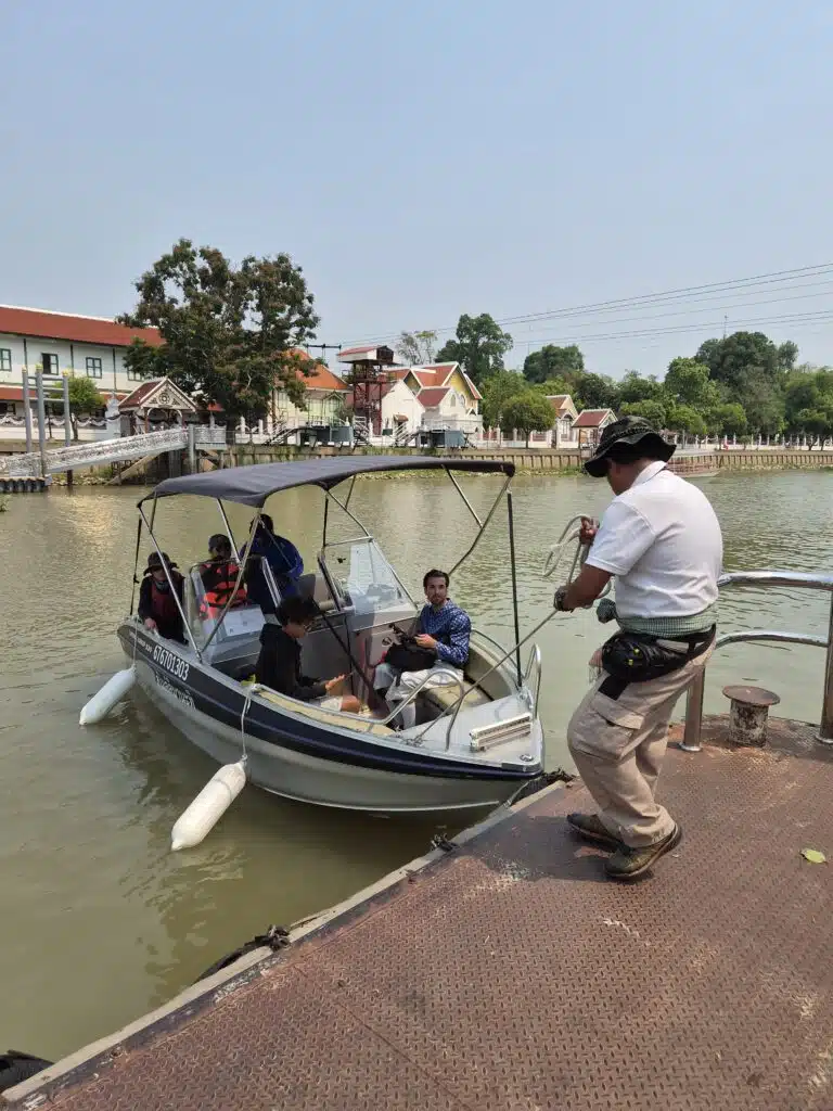 Guests and a local guide boarding a private motorboat at a riverside pier in Ayutthaya.