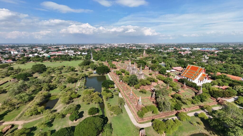 Aerial view of ancient temple ruins and green grounds in Ayutthaya Historical Park, Thailand.